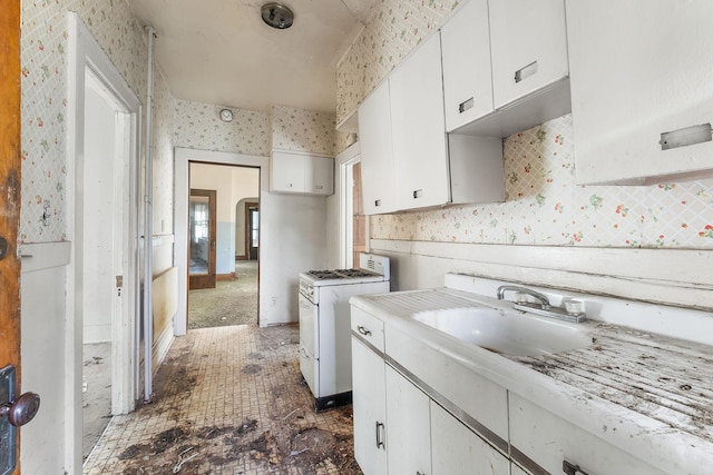 2416 13th Ave S, Minneapolis, MN 55404 - kitchen featuring white range with gas stovetop, wallpapered walls, white cabinetry, light countertops, and arched walkways