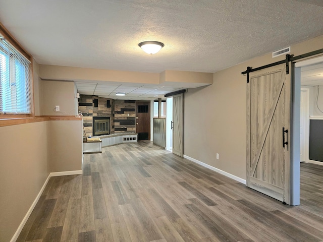 1218 2nd Ave E, International Falls, MN 56649 - unfurnished living room with a barn door, wood finished floors, a fireplace, and a textured ceiling