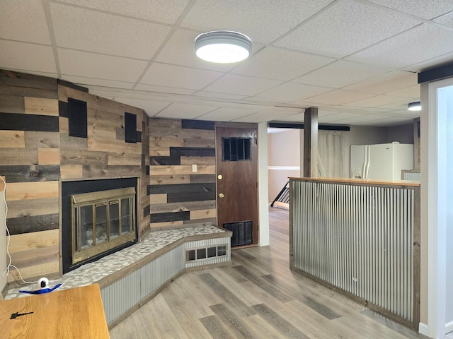 1218 2nd Ave E, International Falls, MN 56649 - unfurnished living room featuring wooden walls, a glass covered fireplace, wood finished floors, and a paneled ceiling