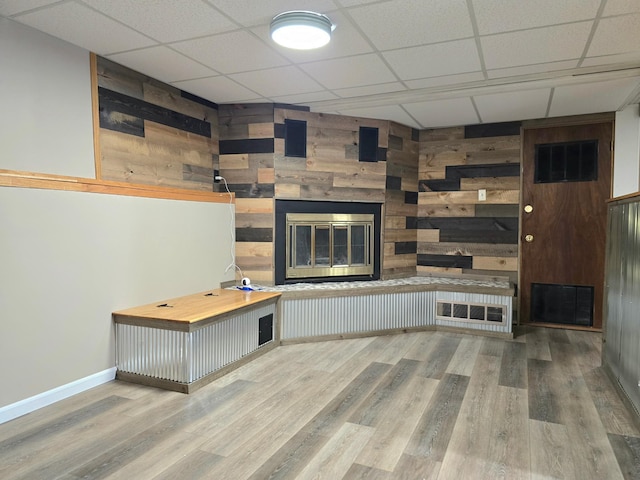 1218 2nd Ave E, International Falls, MN 56649 - unfurnished living room with a fireplace, wooden walls, a paneled ceiling, and wood finished floors
