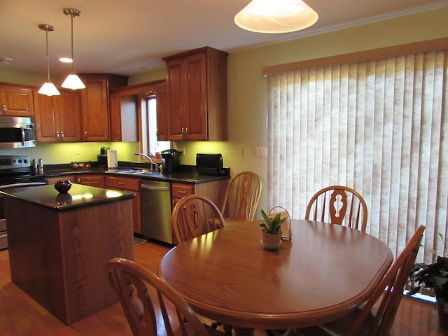 1575 Cornerstone Ln, Owatonna, MN 55060 - kitchen with appliances with stainless steel finishes, dark countertops, a kitchen island, wood finished floors, and brown cabinets