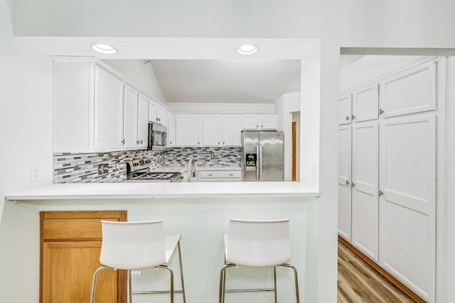 6873 Benton Way Unit 59, Inver Grove Heights, MN 55076 - kitchen with appliances with stainless steel finishes, backsplash, light countertops, white cabinetry, and a kitchen bar