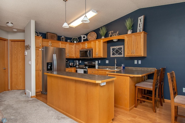 3590 Fillmore St S, Fargo, ND 58104 - kitchen featuring lofted ceiling, stainless steel appliances, a kitchen bar, a peninsula, and decorative light fixtures