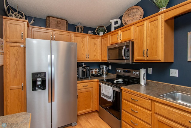3590 Fillmore St S, Fargo, ND 58104 - kitchen featuring stainless steel appliances, dark countertops, a textured ceiling, and light wood-style flooring