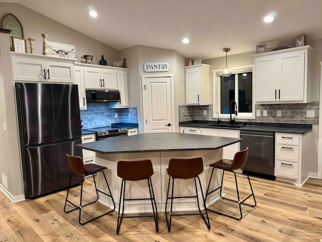 23900 Taurus St, Linwood Twp, MN 55079 - kitchen with appliances with stainless steel finishes, vaulted ceiling, dark countertops, a kitchen breakfast bar, and white cabinetry