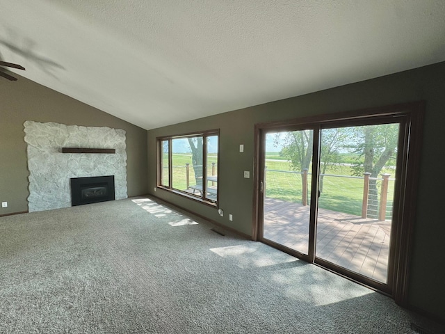 90760 US Highway 71, Christiania Twp, MN 56101 - unfurnished living room with vaulted ceiling, carpet floors, a ceiling fan, a fireplace, and a textured ceiling