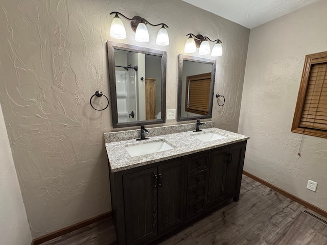 90760 US Highway 71, Christiania Twp, MN 56101 - bathroom with wood finished floors, double vanity, a textured wall, and a shower