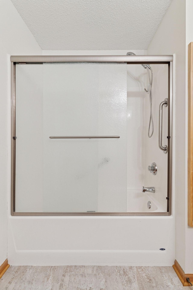 2231 Penn Pl Unit 224, North Saint Paul, MN 55109 - bathroom with a textured ceiling, shower / bath combination with glass door, and wood finished floors