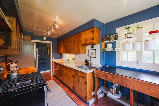 5607 Skogvei Rd, Duluth, MN 55803 - kitchen with black gas stove, brown cabinetry, light countertops, freestanding refrigerator, and track lighting