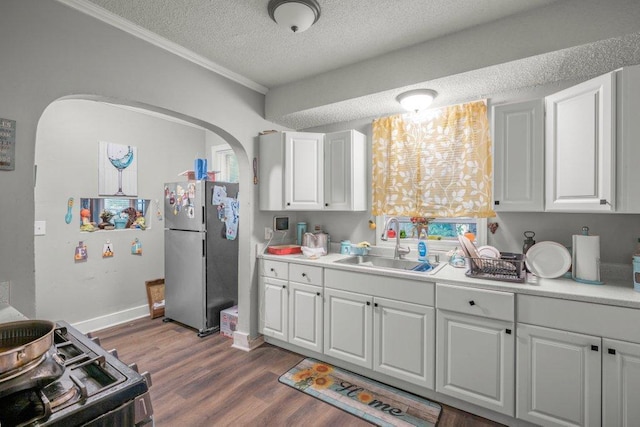 4111 Bryant Ave N, Minneapolis, MN 55412 - kitchen featuring freestanding refrigerator, a textured ceiling, arched walkways, white cabinets, and gas stove