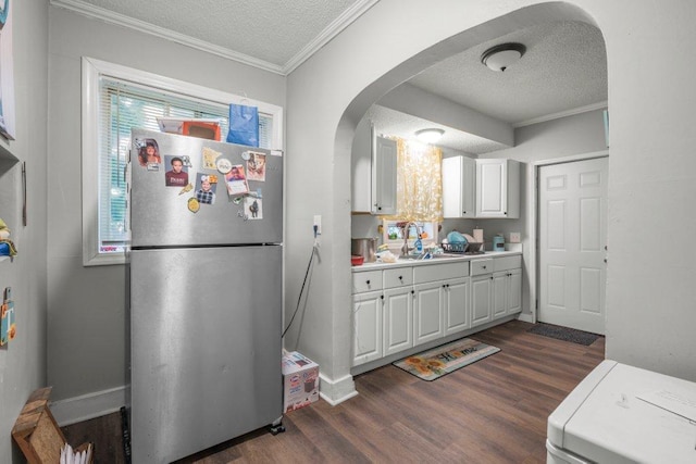 4111 Bryant Ave N, Minneapolis, MN 55412 - kitchen with freestanding refrigerator, a textured ceiling, dark wood-style floors, arched walkways, and white cabinets