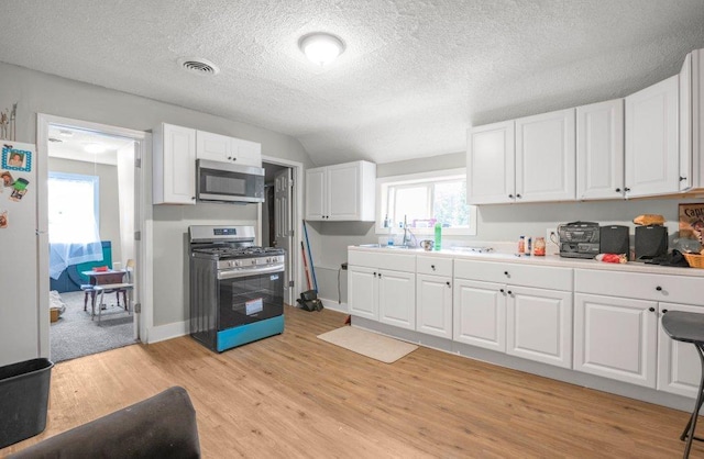 4111 Bryant Ave N, Minneapolis, MN 55412 - kitchen featuring stainless steel appliances, white cabinets, light wood-type flooring, light countertops, and a textured ceiling