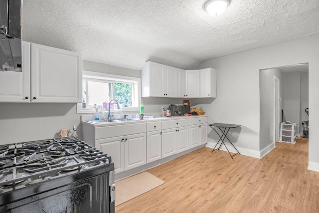 4111 Bryant Ave N, Minneapolis, MN 55412 - kitchen with black gas range oven, light wood finished floors, white cabinets, a textured ceiling, and light countertops