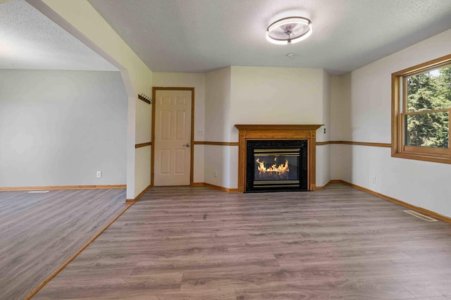 51800 500th St, Menahga, MN 56464 - unfurnished living room featuring wood finished floors, a fireplace with flush hearth, and a textured ceiling