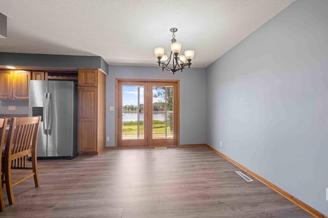 51800 500th St, Menahga, MN 56464 - unfurnished dining area featuring a chandelier, wood finished floors, a water view, and a textured ceiling