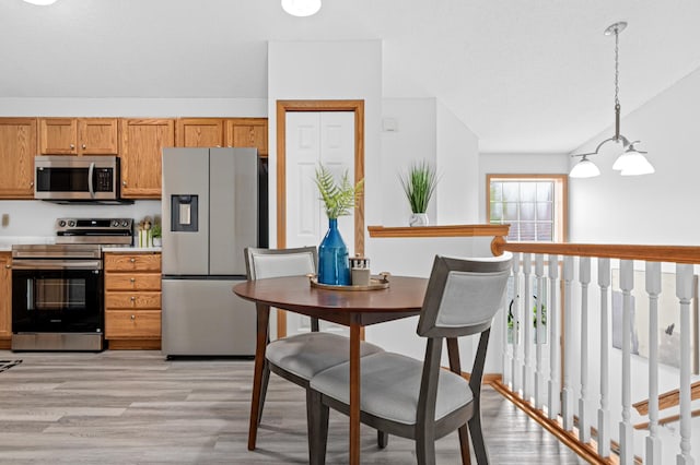 8811 Coffman Path, Inver Grove Heights, MN 55076 - kitchen featuring stainless steel appliances, light wood finished floors, hanging light fixtures, and brown cabinetry