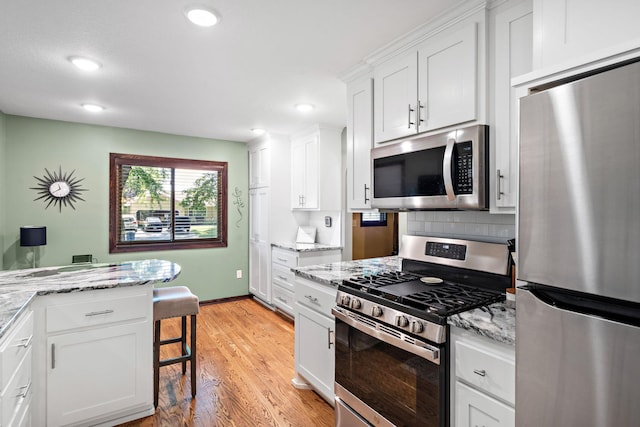 10315 Boundary Creek Ter, Maple Grove, MN 55369 - kitchen featuring appliances with stainless steel finishes, light wood-type flooring, white cabinets, light stone countertops, and recessed lighting