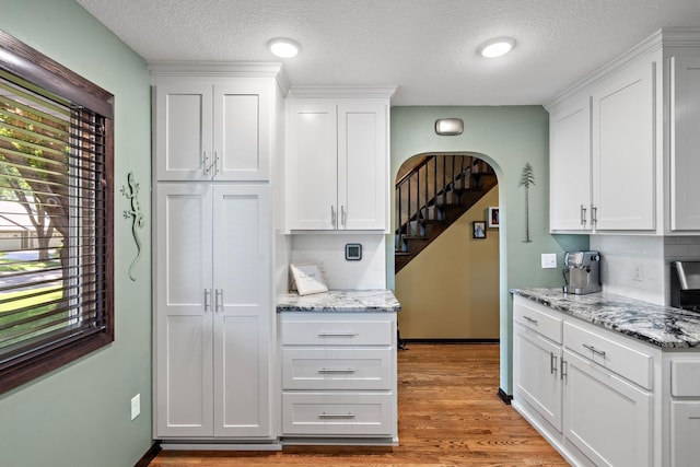 10315 Boundary Creek Ter, Maple Grove, MN 55369 - kitchen featuring arched walkways, white cabinets, backsplash, and a textured ceiling