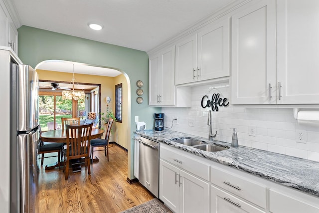 10315 Boundary Creek Ter, Maple Grove, MN 55369 - kitchen with arched walkways, white cabinetry, stainless steel appliances, decorative backsplash, and light wood-style floors