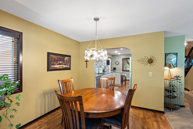 10315 Boundary Creek Ter, Maple Grove, MN 55369 - dining room featuring stairs, wood finished floors, a chandelier, and arched walkways