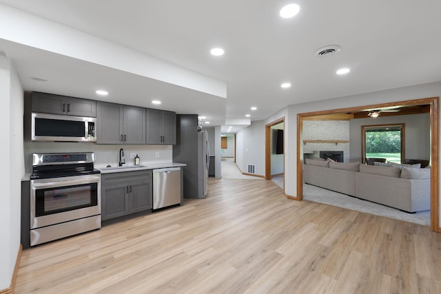 8045 County Road 116, Corcoran, MN 55340 - kitchen featuring gray cabinets, stainless steel appliances, light wood-style floors, a fireplace, and recessed lighting