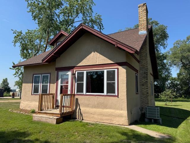 31845 615th Ave, Compton Twp, MN 56482 - view of front facade with stucco siding, a front lawn, a chimney, and roof with shingles