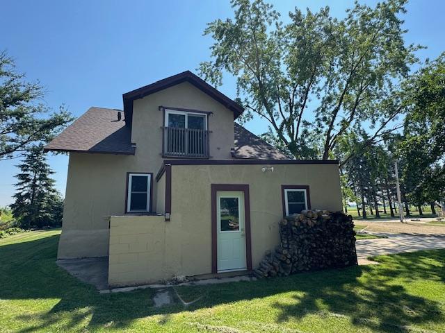 31845 615th Ave, Compton Twp, MN 56482 - rear view of house featuring a shingled roof, a lawn, and stucco siding