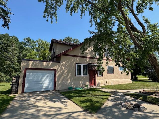 31845 615th Ave, Compton Twp, MN 56482 - view of front of house with concrete driveway, an attached garage, stucco siding, and a front lawn