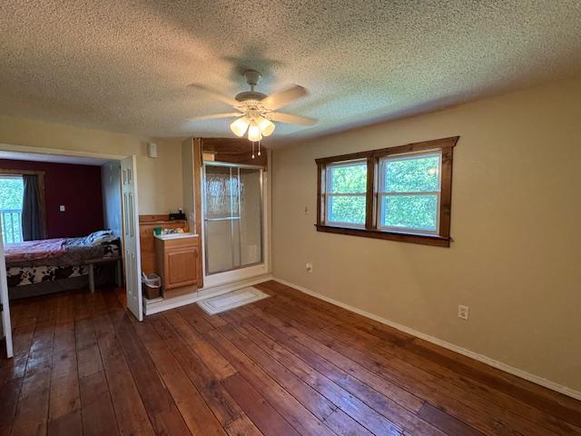 31845 615th Ave, Compton Twp, MN 56482 - unfurnished bedroom with dark wood-style flooring, a textured ceiling, and a ceiling fan