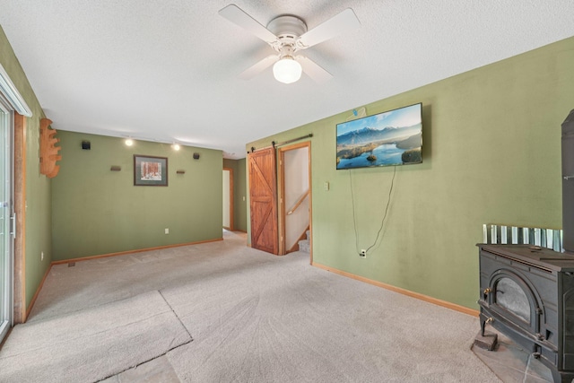 24864 Kettle River Blvd, Wyoming, MN 55025 - unfurnished living room featuring a wood stove, a barn door, carpet flooring, ceiling fan, and a textured ceiling