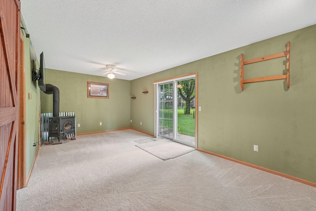24864 Kettle River Blvd, Wyoming, MN 55025 - unfurnished living room featuring a wood stove, carpet flooring, ceiling fan, and a textured ceiling