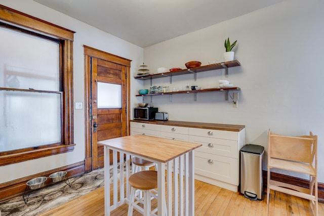 400 8th Ave NE Unit 1, Minneapolis, MN 55413 - kitchen with wood counters, white cabinetry, light wood-style floors, stainless steel microwave, and open shelves