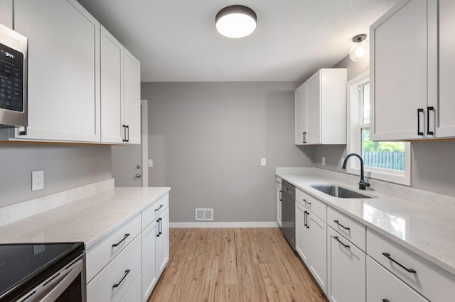 11632 Utah Ave N, Champlin, MN 55316 - kitchen with light wood-style flooring, white cabinetry, stainless steel appliances, and light stone countertops