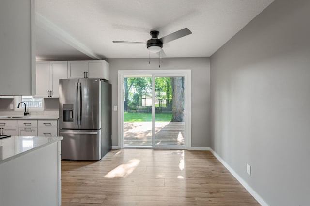 11632 Utah Ave N, Champlin, MN 55316 - kitchen with stainless steel fridge with ice dispenser, light countertops, a ceiling fan, white cabinetry, and light wood-type flooring