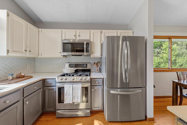 14349 Natchez Ave, Savage, MN 55378 - kitchen featuring stainless steel appliances, light countertops, a textured ceiling, light wood-type flooring, and decorative backsplash