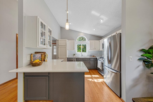14349 Natchez Ave, Savage, MN 55378 - kitchen with lofted ceiling, a peninsula, stainless steel appliances, light wood-style flooring, and backsplash