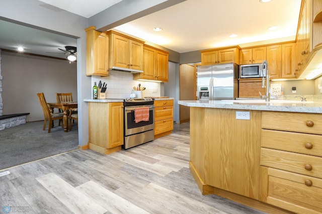 921 16th St S, Fargo, ND 58103 - kitchen featuring stainless steel appliances, ceiling fan, backsplash, light wood-style flooring, and light stone countertops