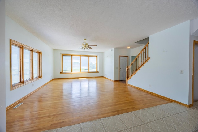 23865 County Rd, Loretto, MN 55357 - unfurnished living room featuring light wood-style flooring, a ceiling fan, stairway, and a textured ceiling