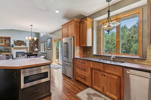 13836 Clare Downs Way, Rosemount, MN 55068 - kitchen featuring stainless steel appliances, a textured ceiling, tasteful backsplash, a tile fireplace, and dark wood finished floors