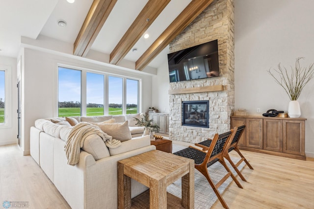 living room featuring beam ceiling, a stone fireplace, light hardwood / wood-style flooring, and high vaulted ceiling