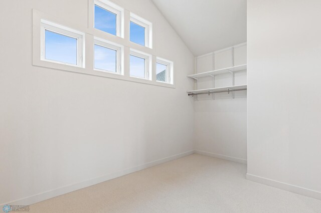 spacious closet featuring light colored carpet and lofted ceiling