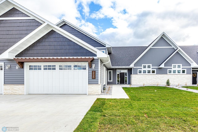5820 31st St S, Fargo, ND 58104 - view of front of home featuring stone siding, a front lawn, concrete driveway, a shingled roof, and an attached garage