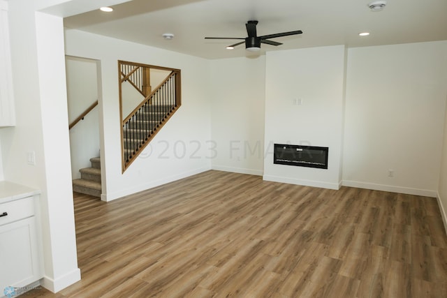 unfurnished living room featuring wood-type flooring, heating unit, and ceiling fan