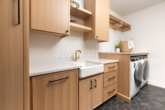 clothes washing area with dark tile patterned floors, cabinets, separate washer and dryer, and sink