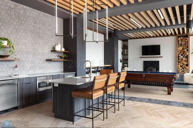 kitchen featuring sink, stainless steel dishwasher, billiards, backsplash, and light parquet flooring