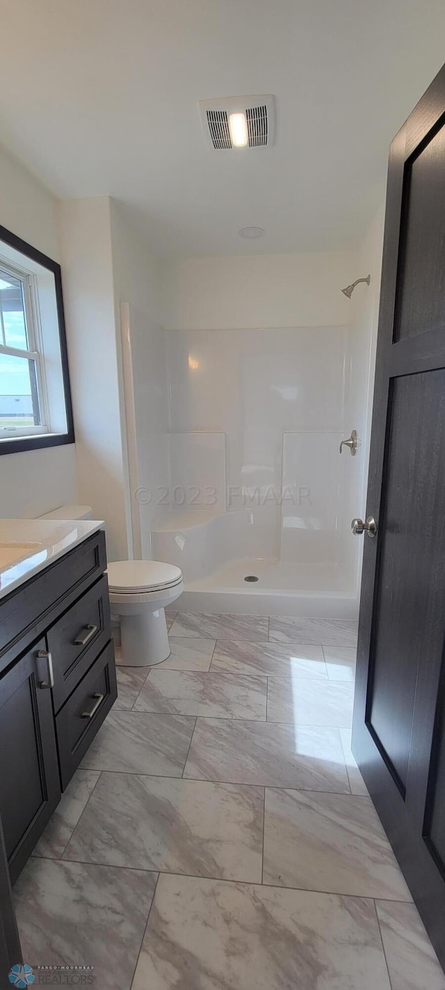 bathroom with a shower, vanity, and toilet