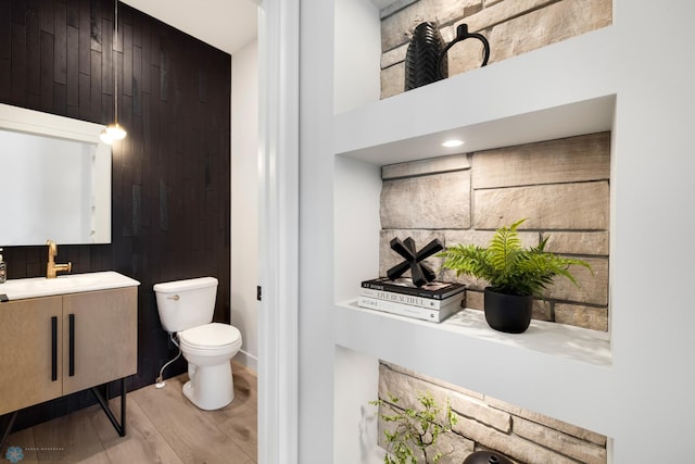 bathroom featuring hardwood / wood-style floors, vanity, toilet, and wooden walls