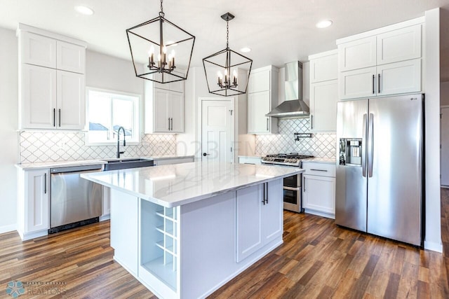 kitchen with sink, wall chimney exhaust hood, a kitchen island, white cabinetry, and stainless steel appliances