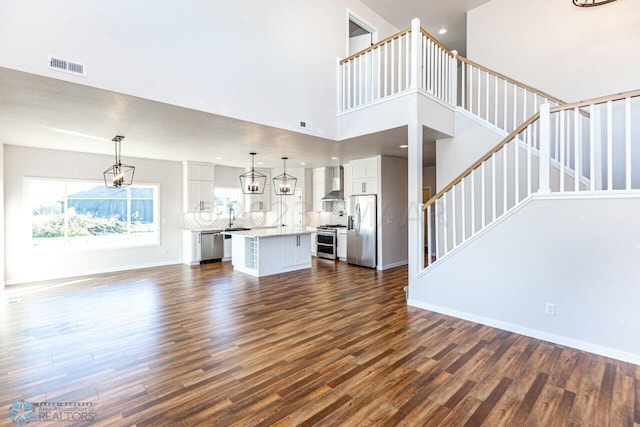 unfurnished living room with sink, dark wood-type flooring, and a high ceiling