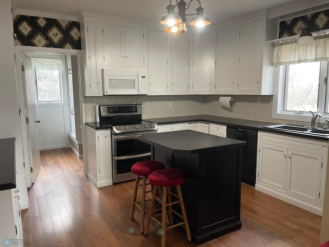 kitchen featuring a center island, sink, white cabinetry, and stainless steel range with electric cooktop